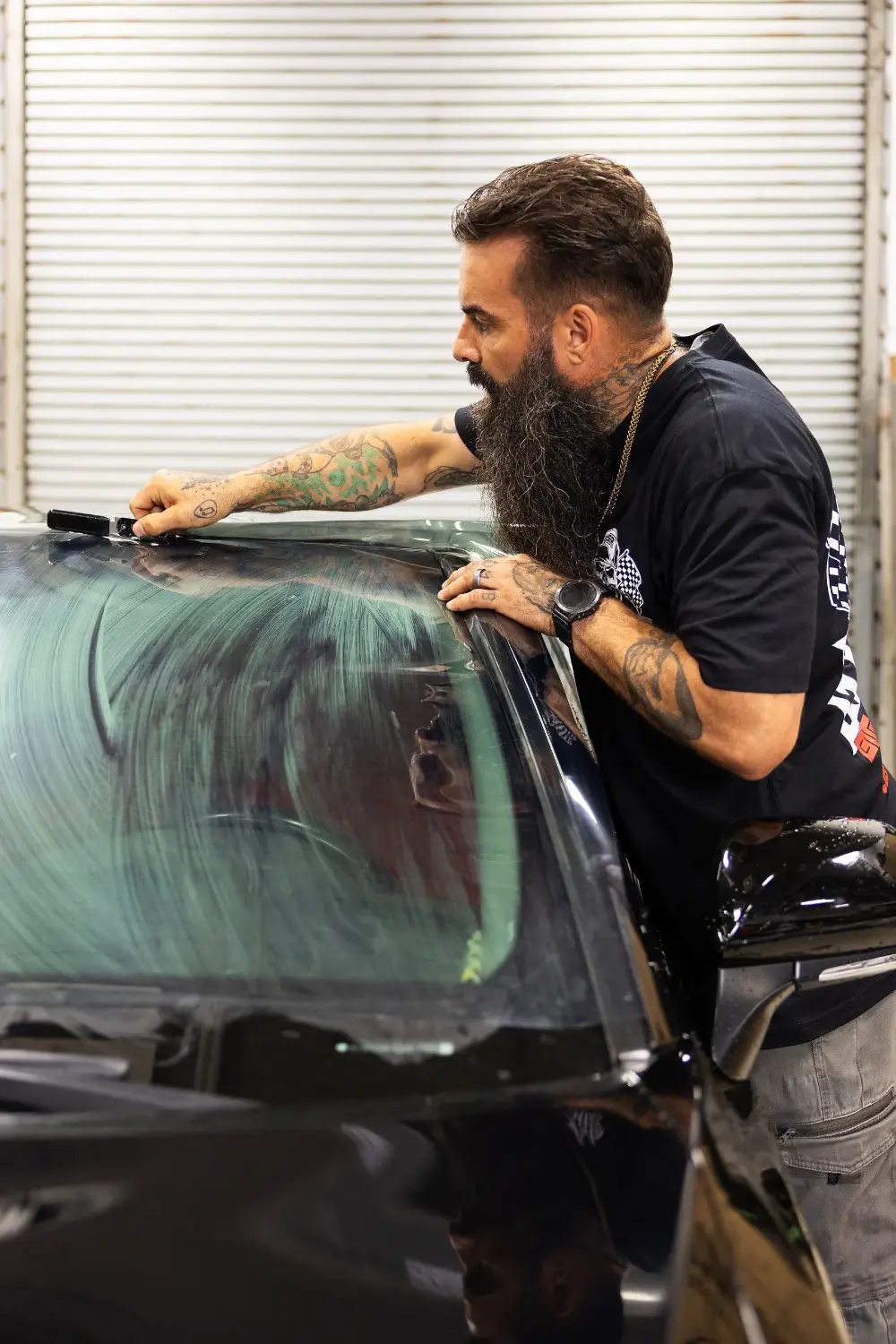 Chris Joerger squeegeeing window film on a windshield in the Big Shot Rides install bay