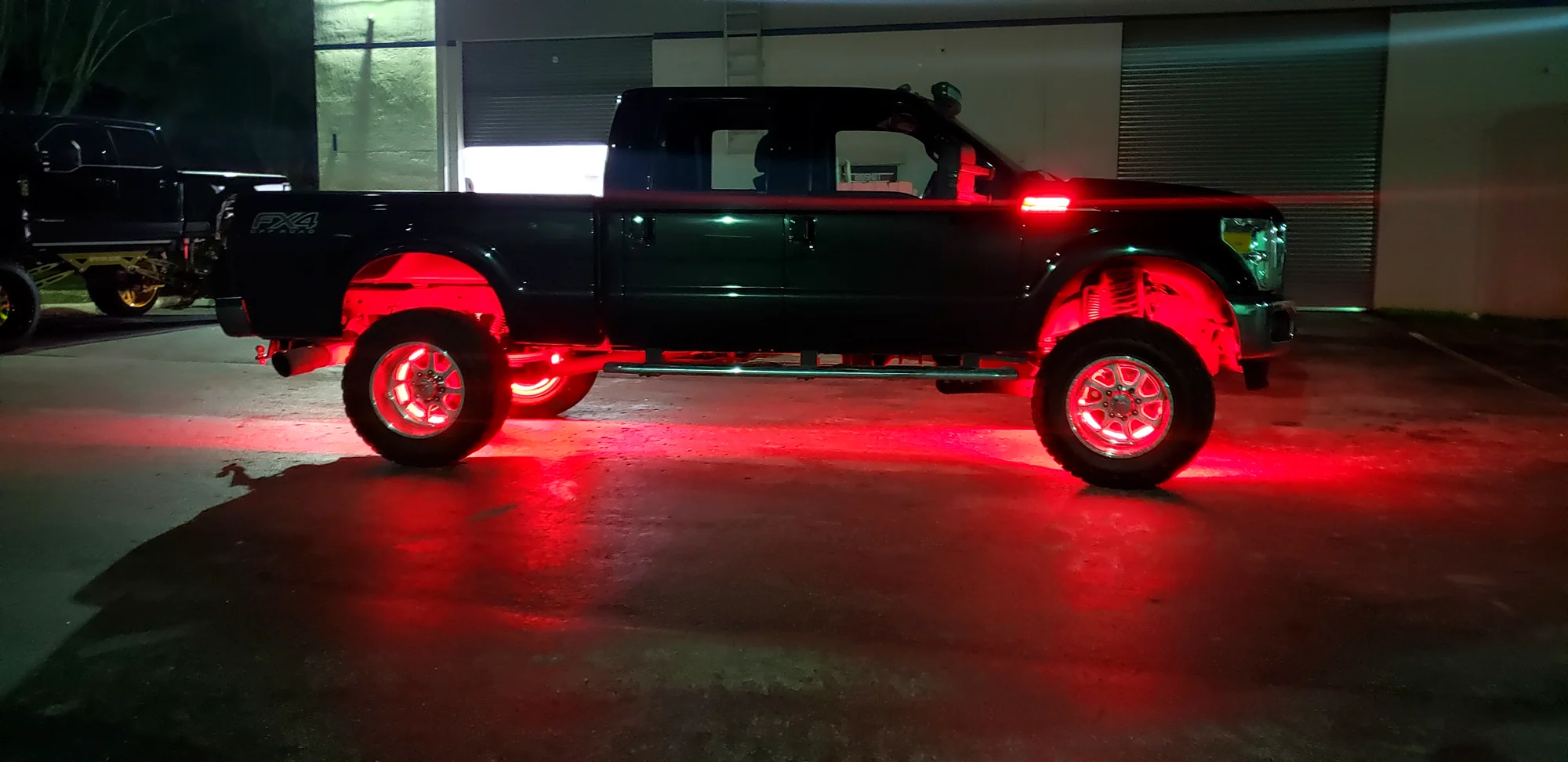 Red LED rock lights installed on a lifted Ford Super Duty at night, Big Shot Rides Coconut Creek FL