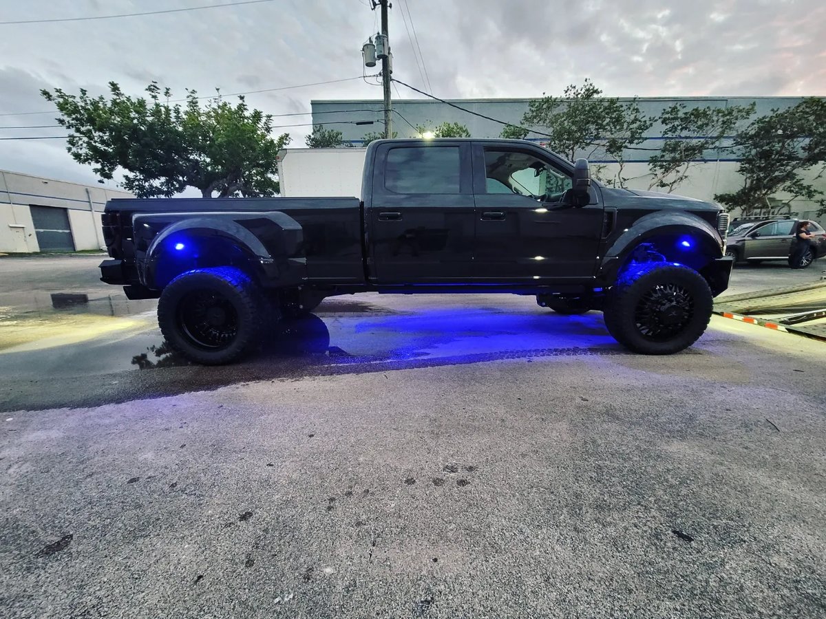 Black Ford F-450 dually with rock lights and LED accessory lighting at dusk in Coconut Creek FL
