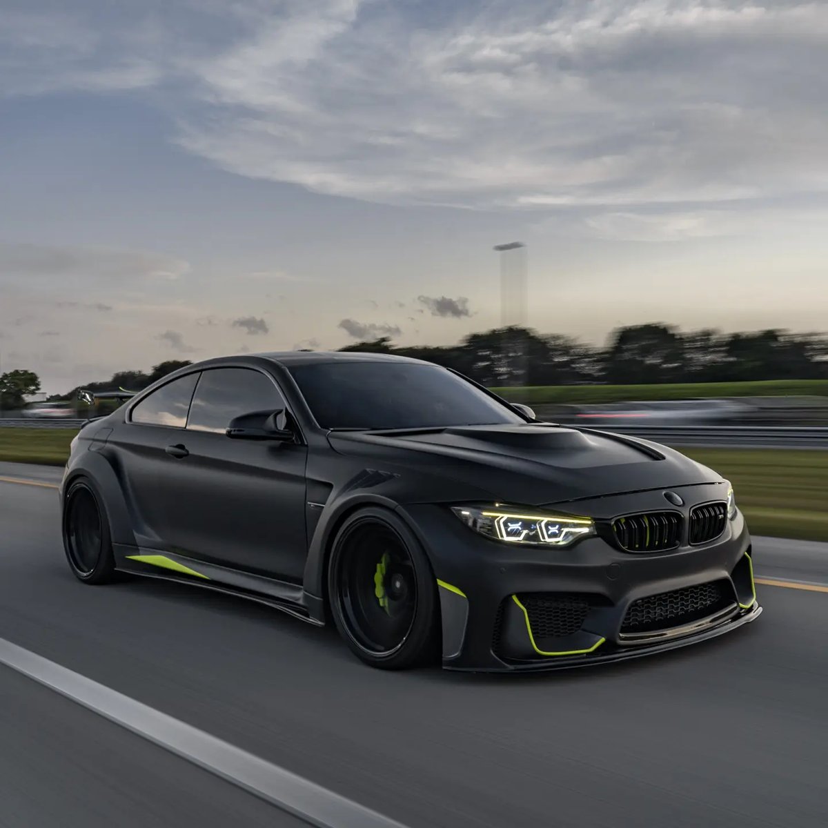 Matte black BMW M4 widebody lowered on coilovers at speed near Coconut Creek FL