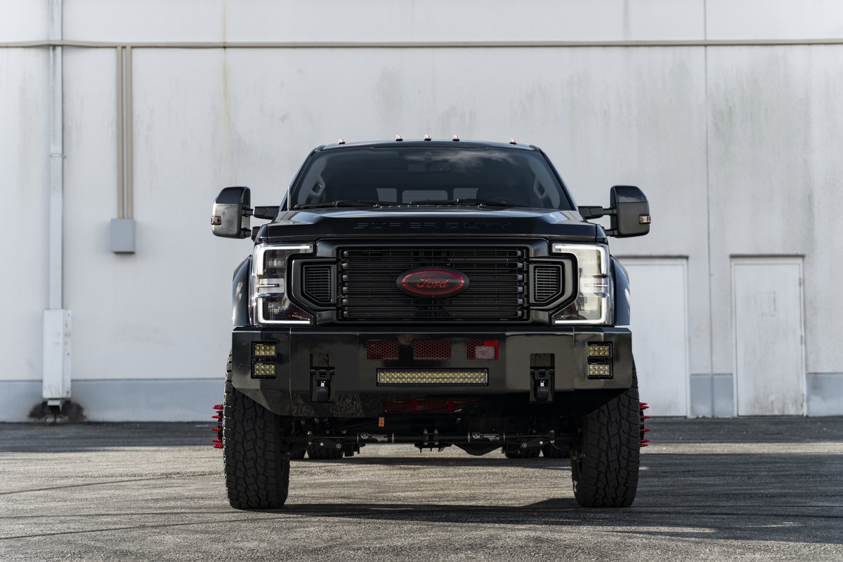 Black Ford F-450 with custom front bumper, red Ford grille emblem, and integrated LED lighting in Coconut Creek FL