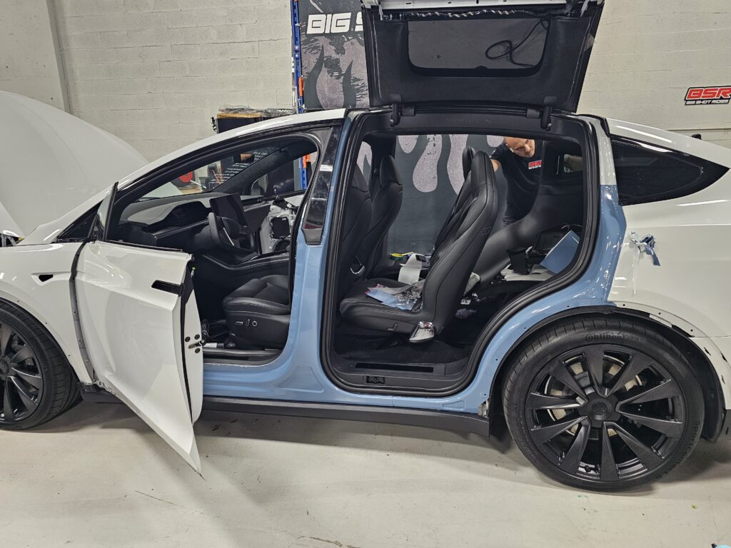 Door jambs wrapped in light blue on a Tesla Model X during a color change at Big Shot Rides in Coconut Creek, Florida